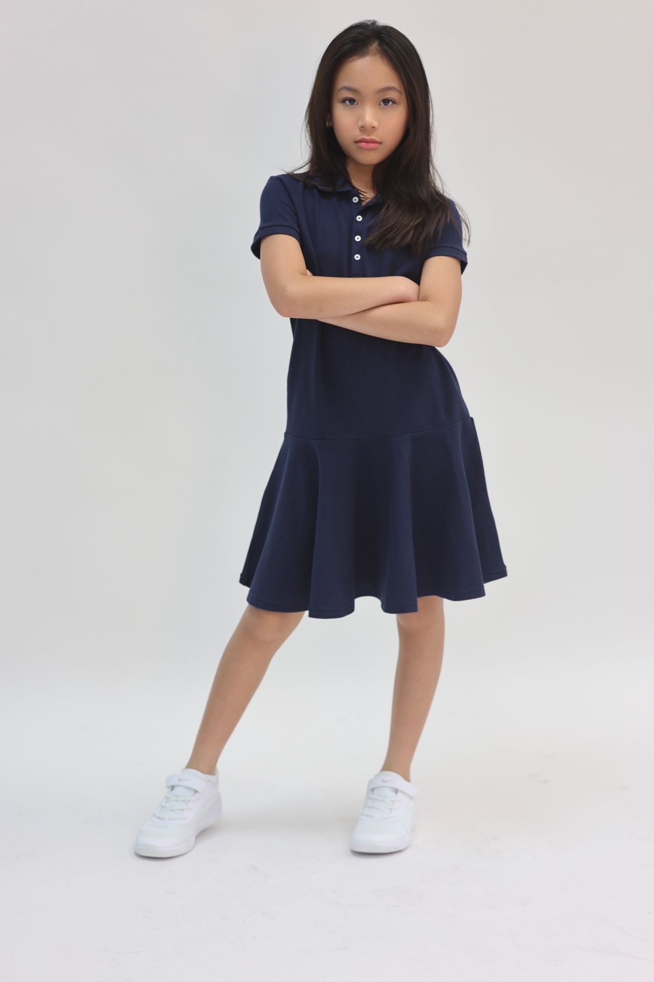 Navy polo drop-waist dress with white sneakers, arms crossed