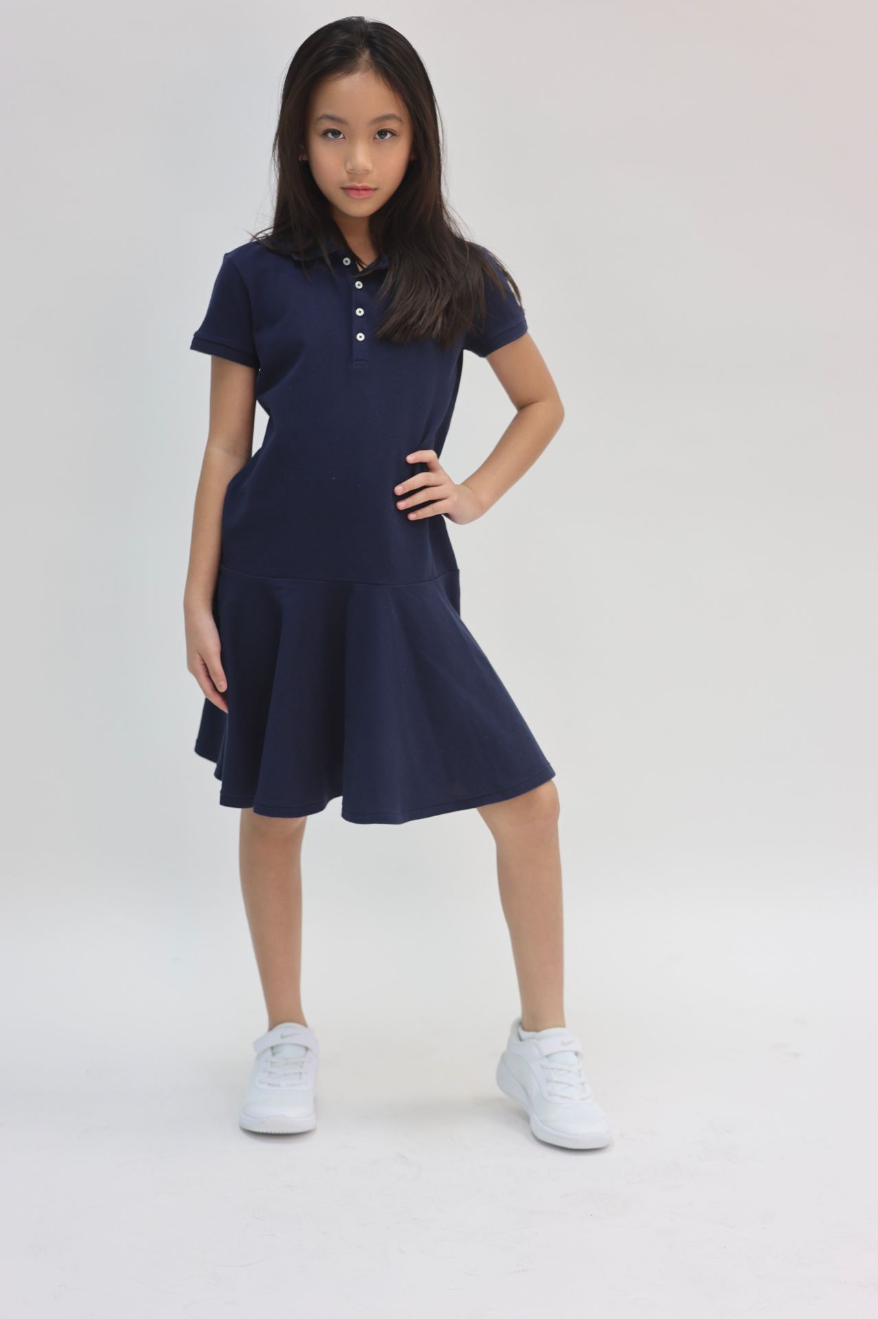 Navy polo drop-waist dress with white sneakers, hand on hip