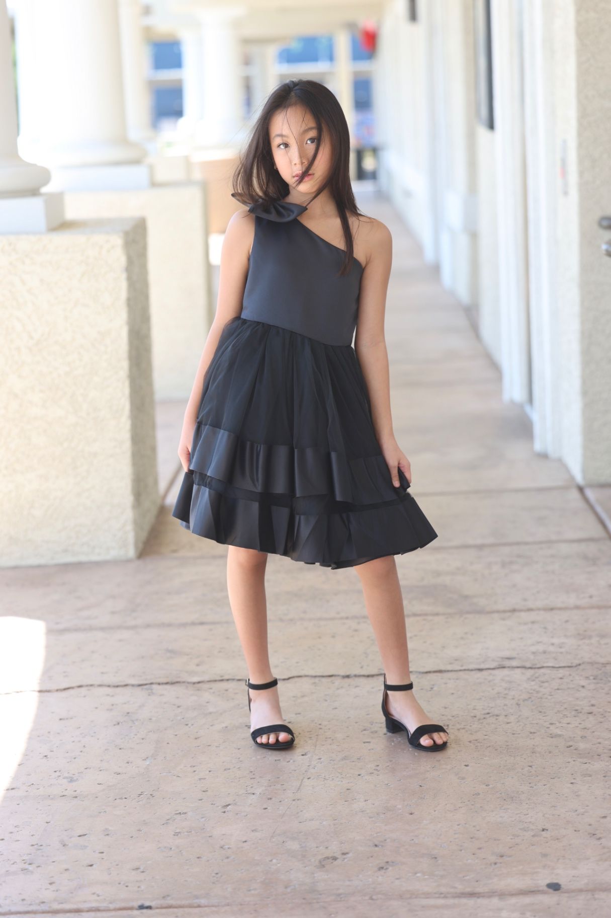 Outdoor editorial in black one-shoulder tiered dress, movement frame